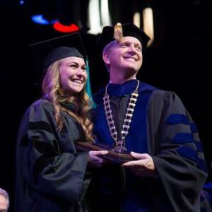 HSU President presents a plaque to a graduating student.